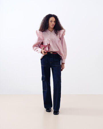 Model in pink shirt and black jeans
