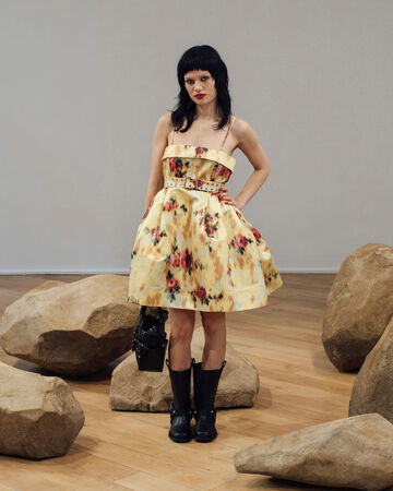Model wearing yellow floral dress with black boots
