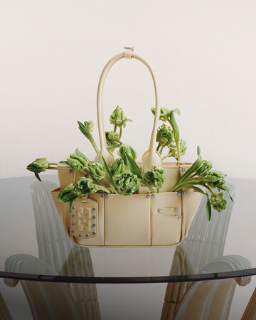 Yellow Posy handbag with flowers inside a placed on a glass table