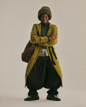 Model wearing a green coat and black pants from the Fall/Winter 2026 collection
