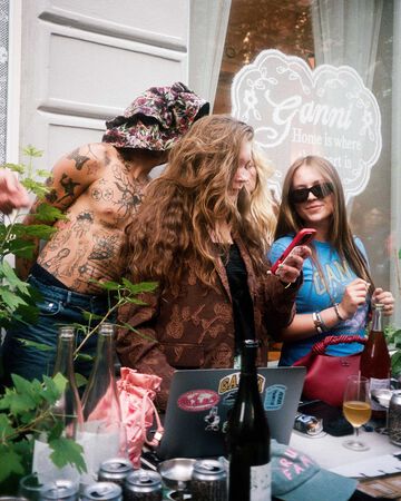 Three people behind a DJ booth at the GANNI x STEM Afterparty