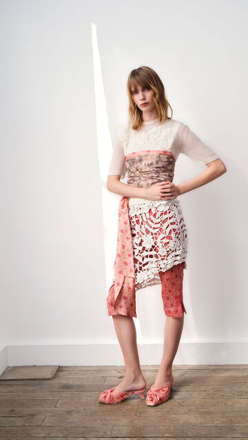 Model wearing a white wrap top, with a skirt and pants