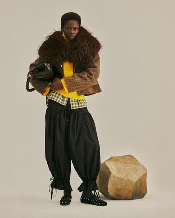 Model standing by rock, wearing GANNI FW26 collection and Very Bou bag
