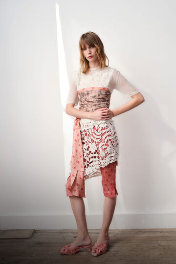 Model wearing a white wrap top, with a skirt and pants