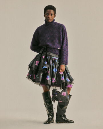 Model wearing a purple knit and floral skirt from the Fall/Winter 2026 collection