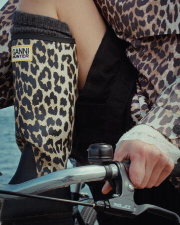 Close-up of model sitting on a bike in leopard rain boots and a leopard rain coat