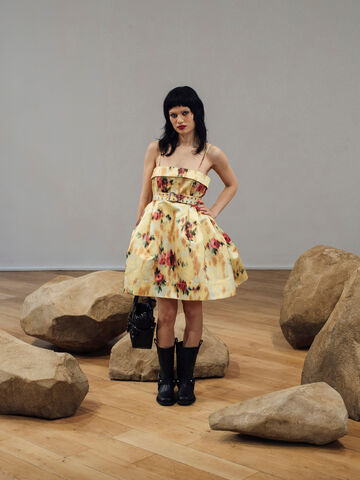 Model wearing a floral dress carrying a black studded handbag