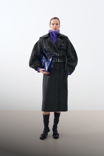 Model wearing grey wool trench coat, purple turtleneck and back small Kat bag